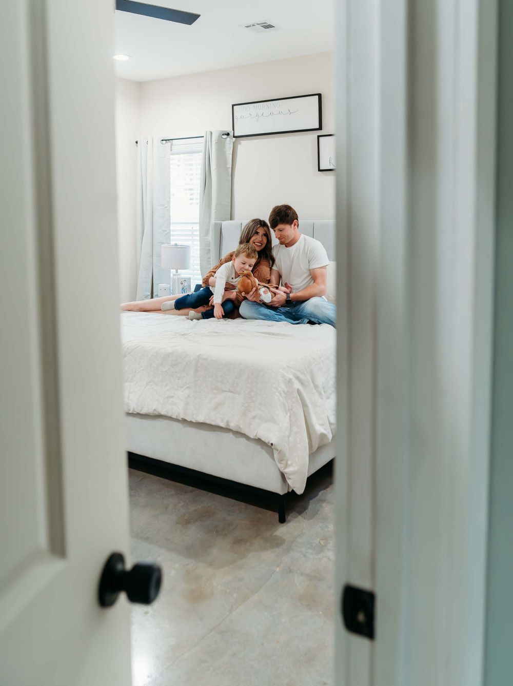 A cozy bedroom scene viewed through a doorway with soft natural light.