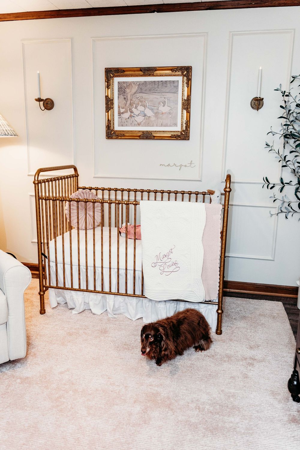 Brown dog lying on plush white carpet beside wooden bed frame with warm lighting and wall decor in bedroom.