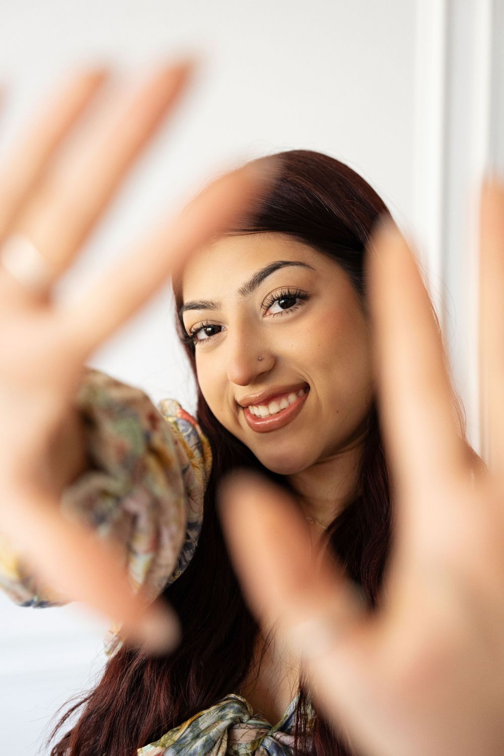 Portrait session with creative hand framing against white background.