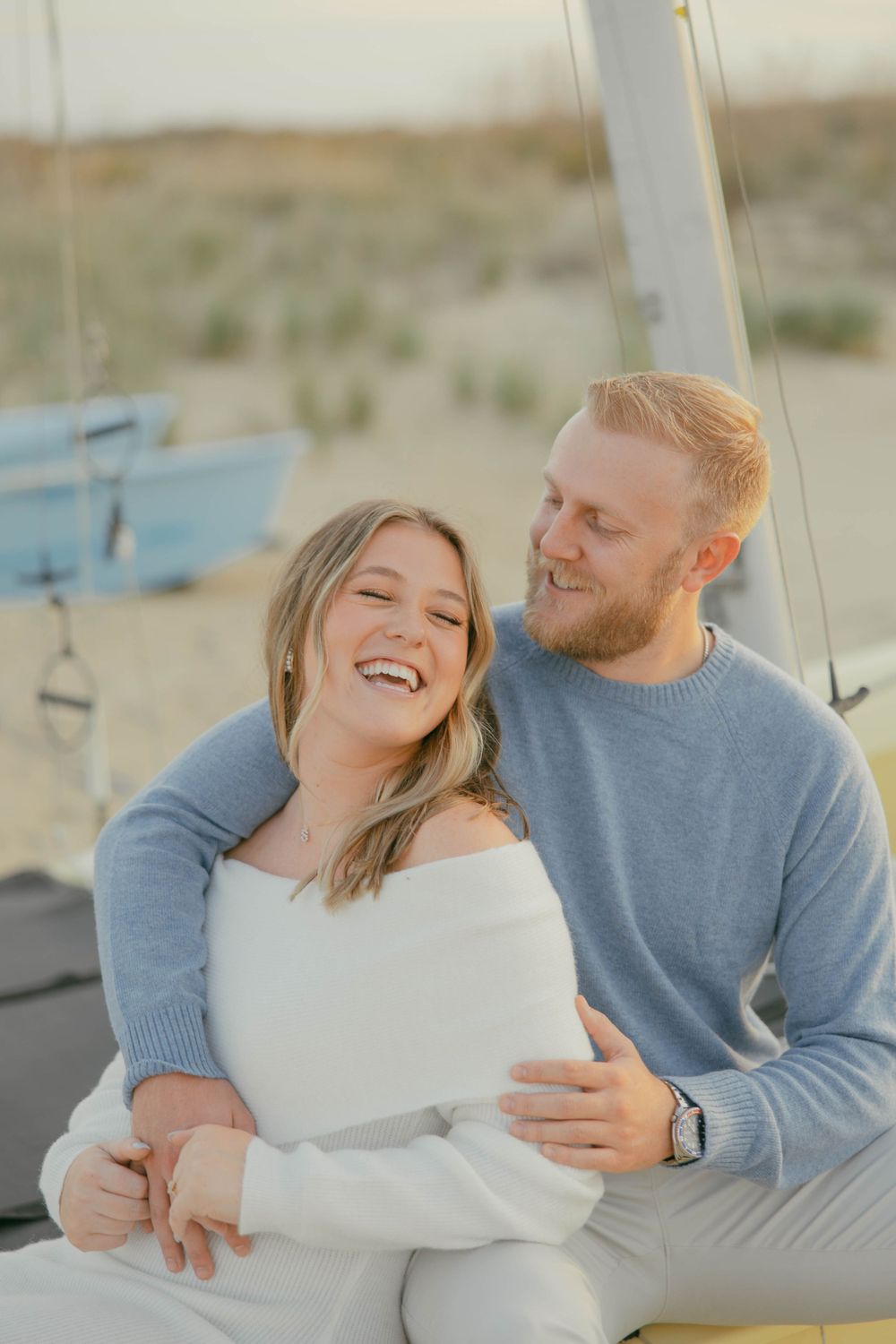 Couple laughing together on sailboat during sunset.