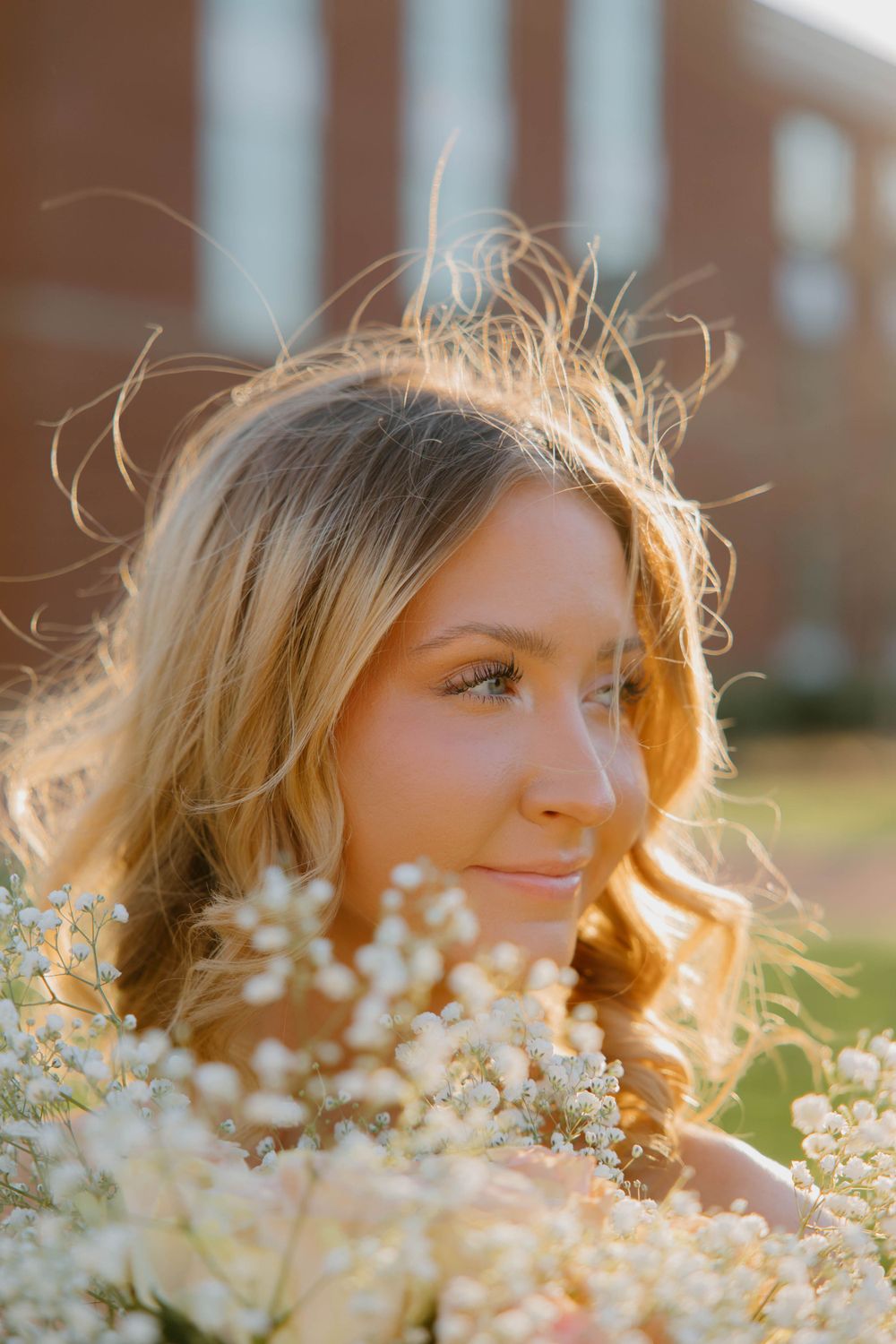 Artistic portrait with sunlit flowers and golden hour lighting.