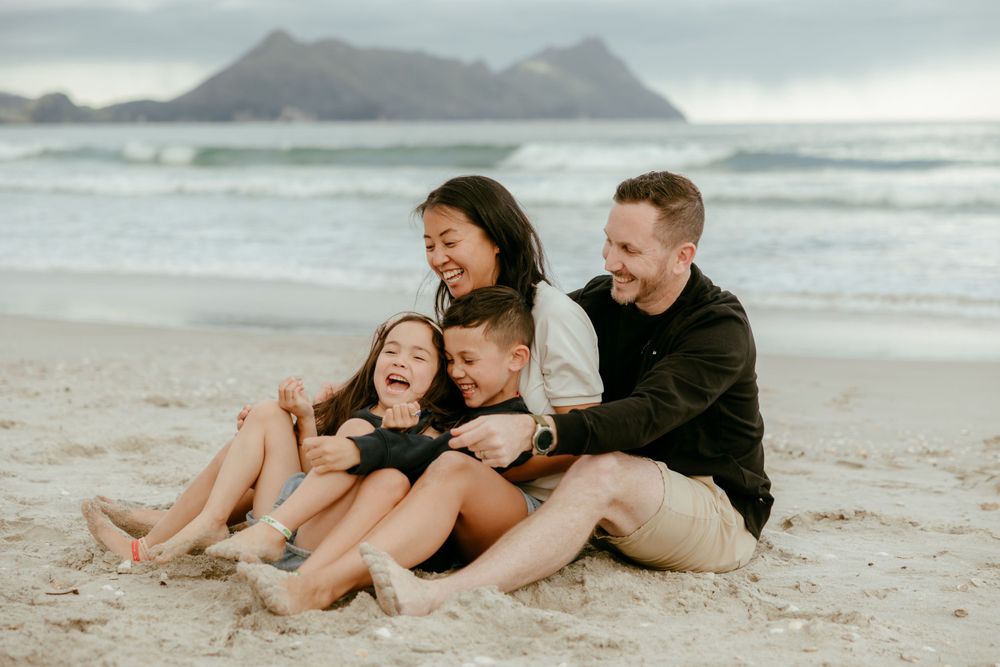 A joyful family moment on a scenic beach with mountains in the background.
