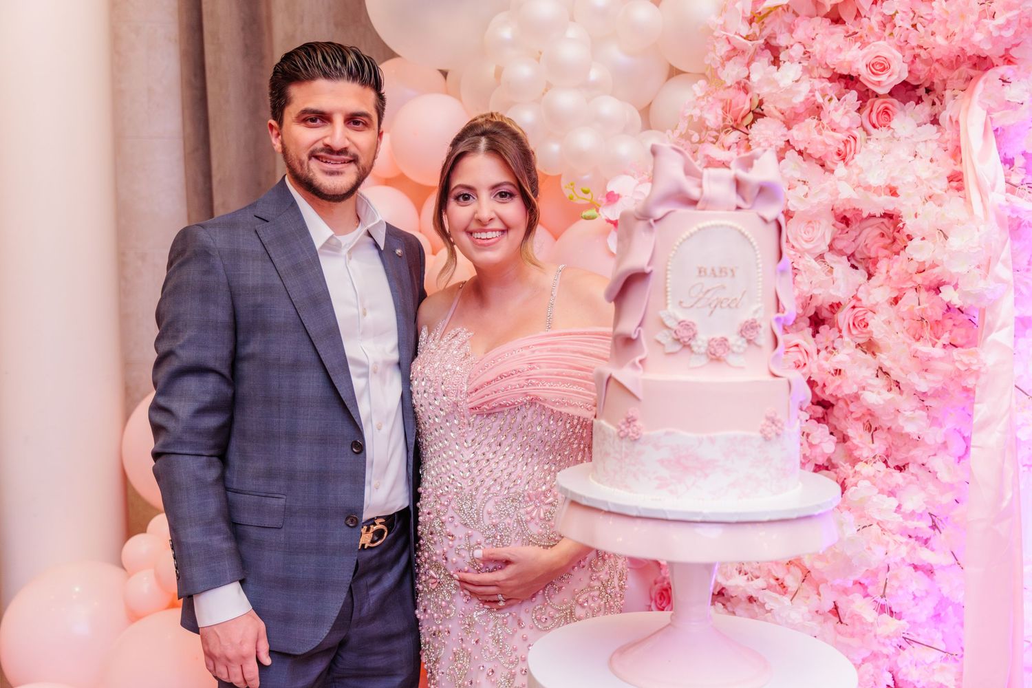 Parents to be stand next to the cake at the baby shower.