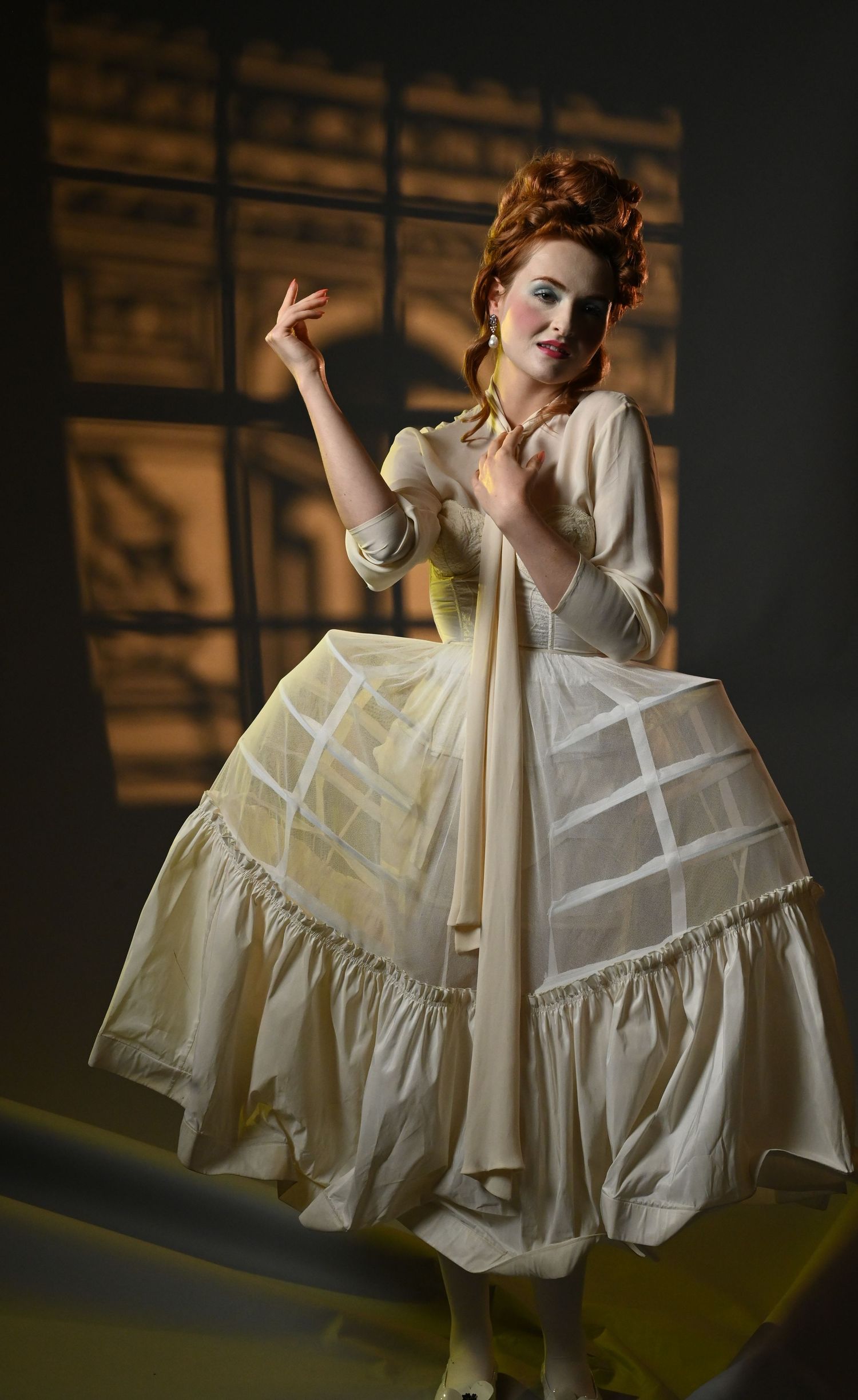 Woman in vibrant green dress with puff sleeves poses elegantly on chair against light background at an event space in Philadelphia, PA.