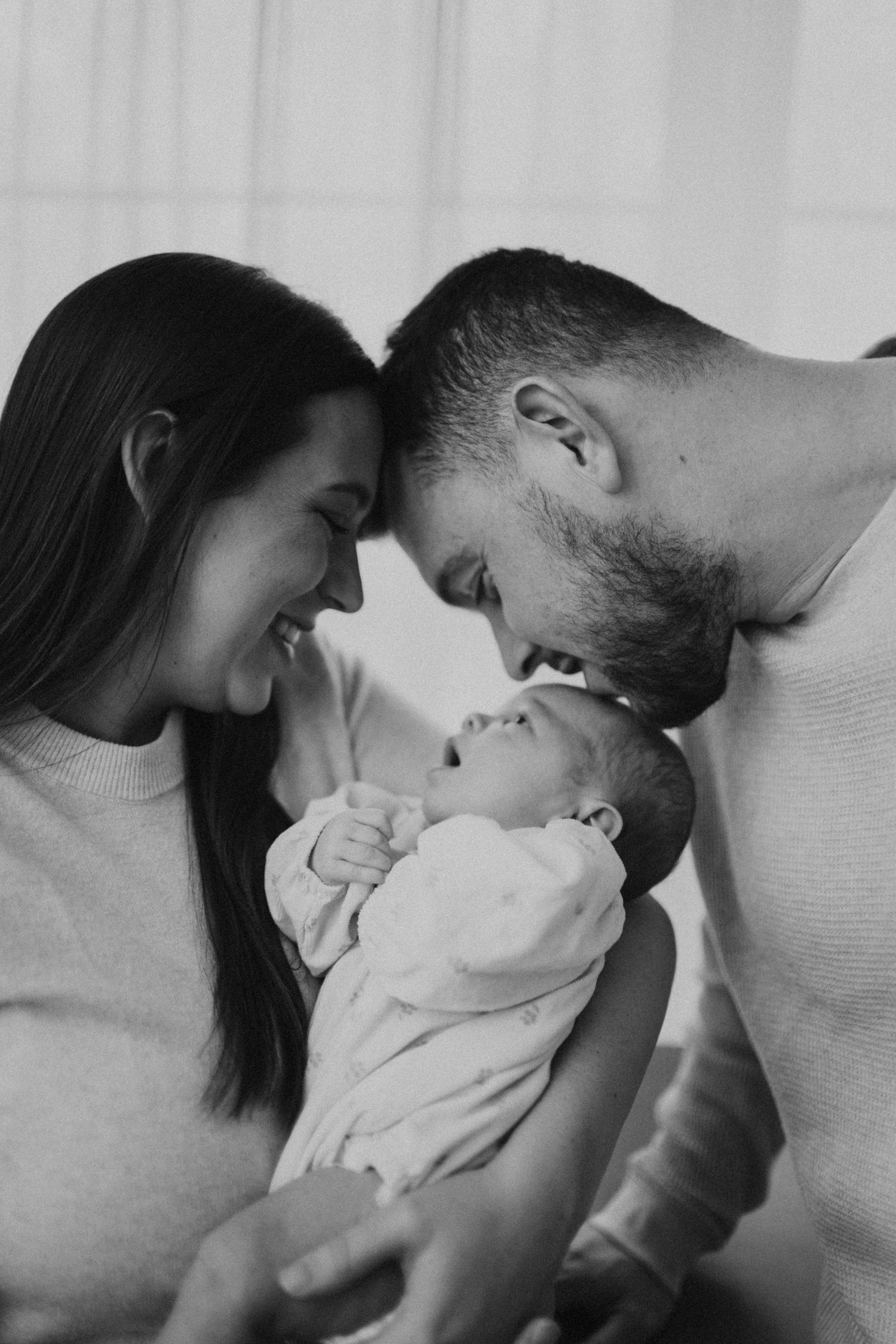 An intimate black and white family moment with a sleeping infant.