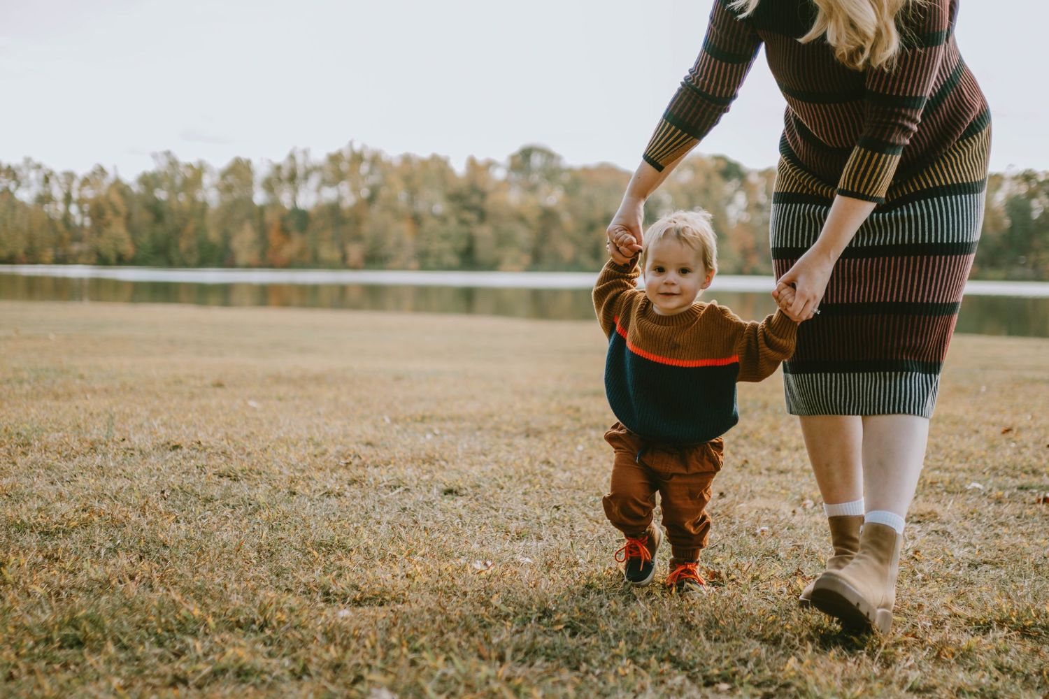 Family walking together across grassy field on autumn day.