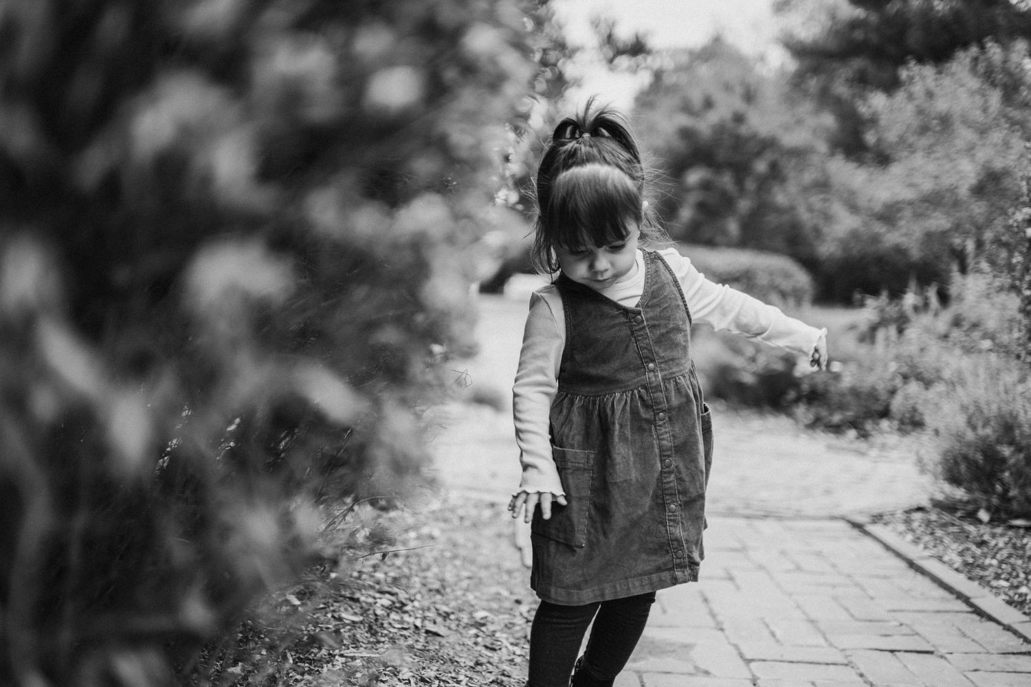 Child walking on outdoor path surrounded by natural greenery.