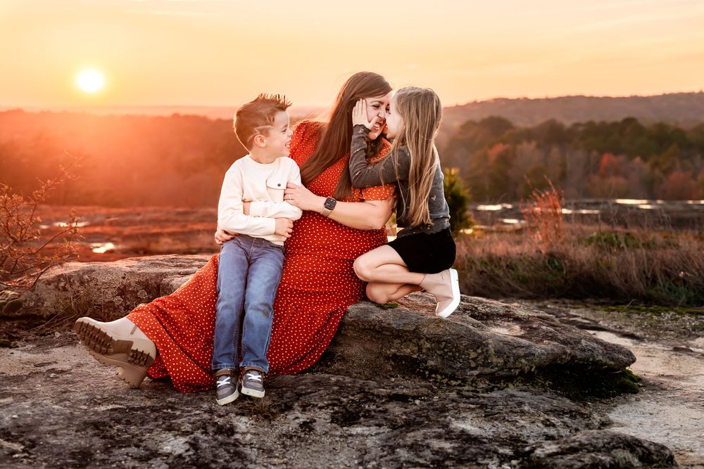 Loving family moment captured during sunset on rocky terrain.