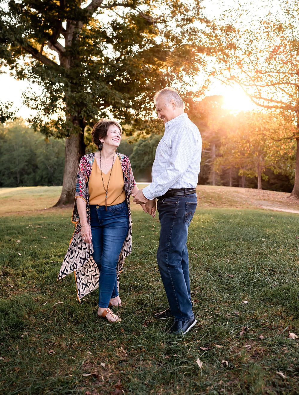 Romantic couple portrait in casual attire against scenic sunset background.
