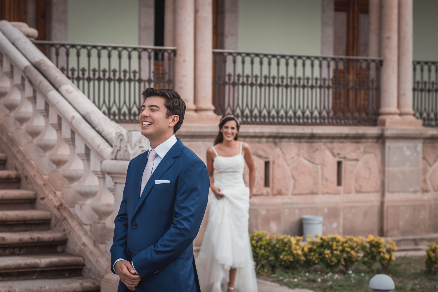 First look wedding moment on stone steps of historic building.