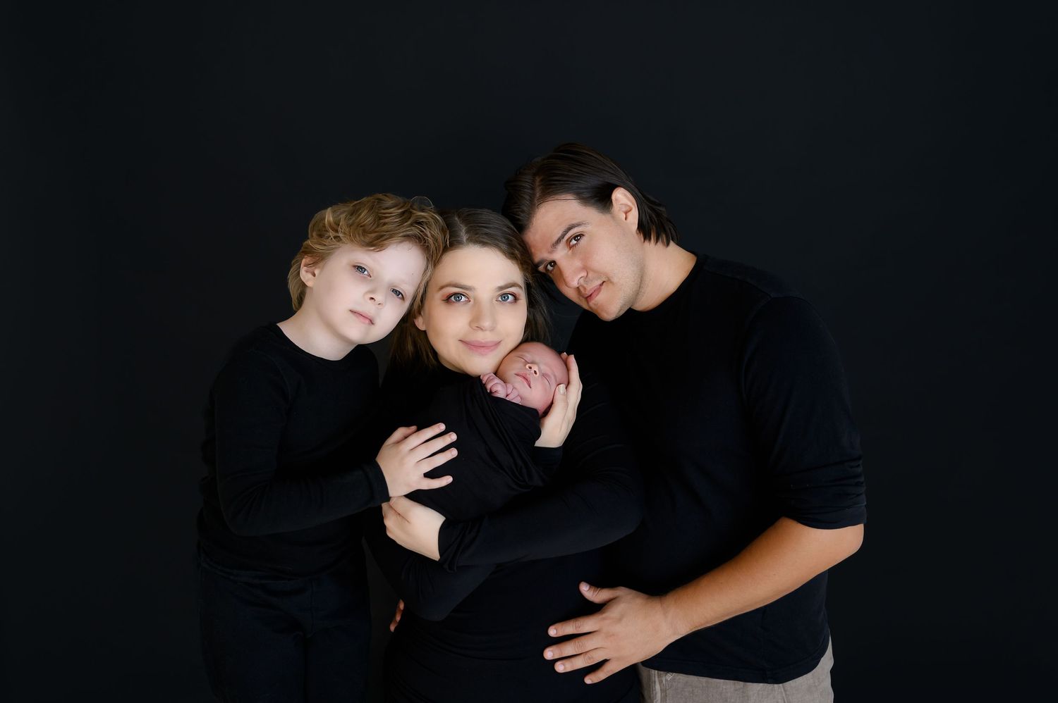 Group portrait of people in black clothing against dark background.