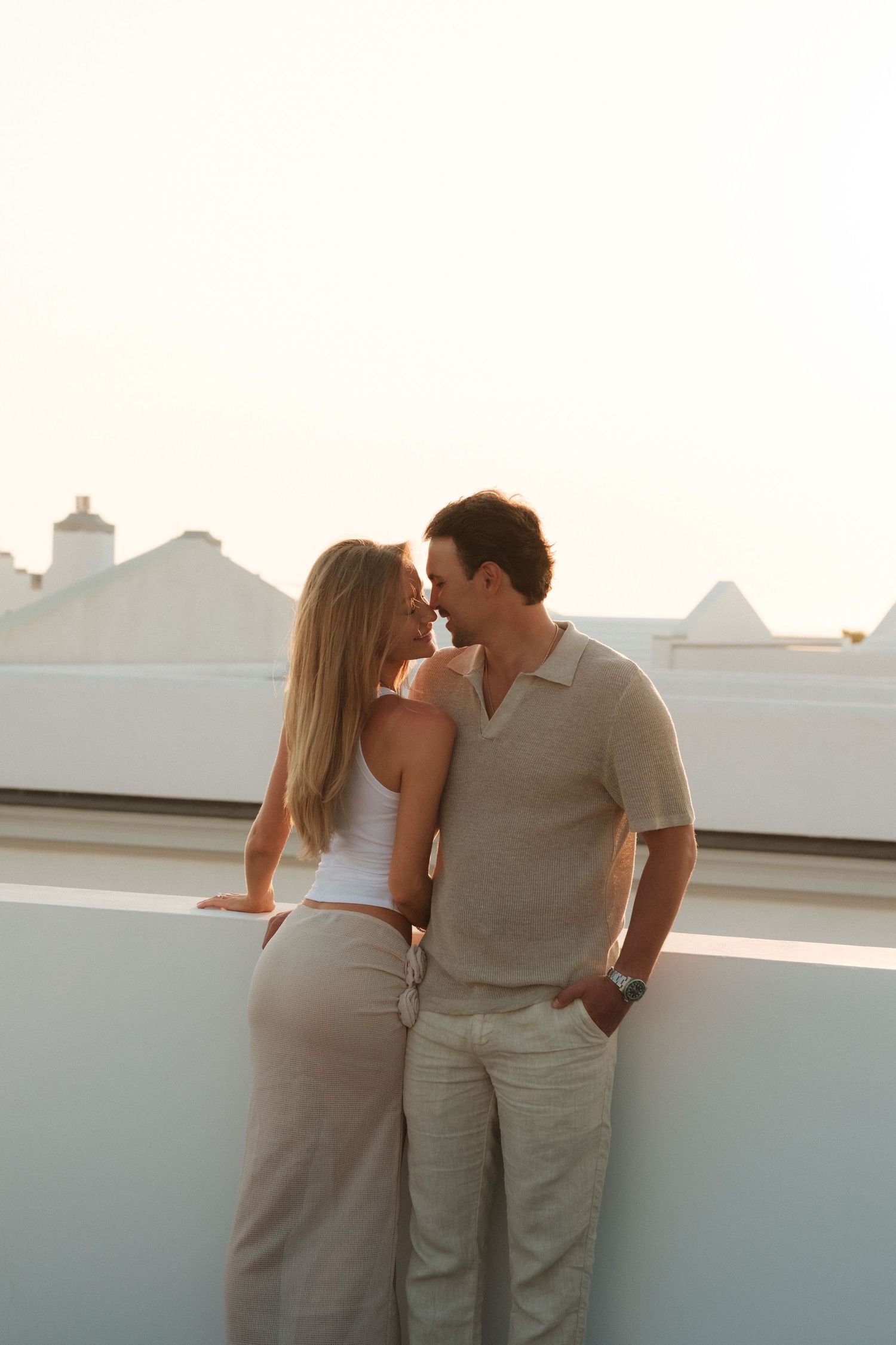 Romantic couple sharing an intimate moment on a rooftop terrace at sunset.