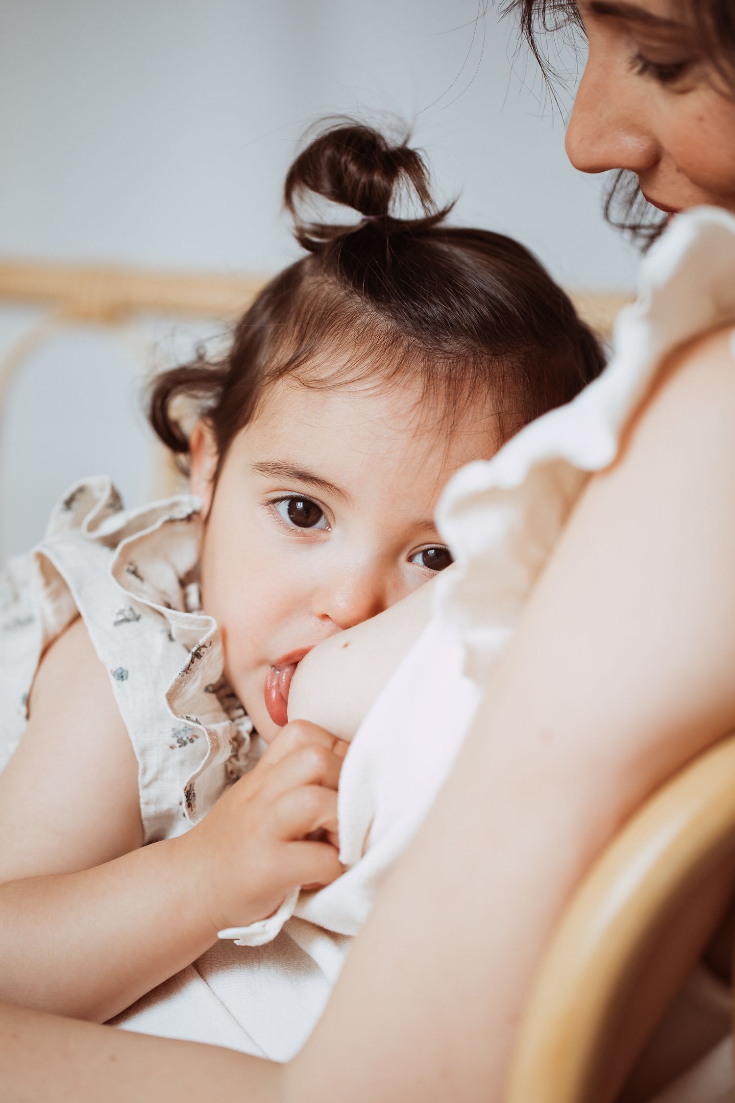 Intimate breastfeeding moment captured in soft natural lighting.