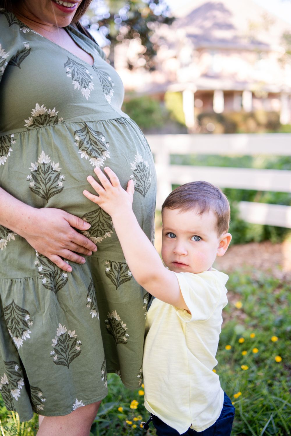 Little boy reaching up to touch his mother's pregnant stomach