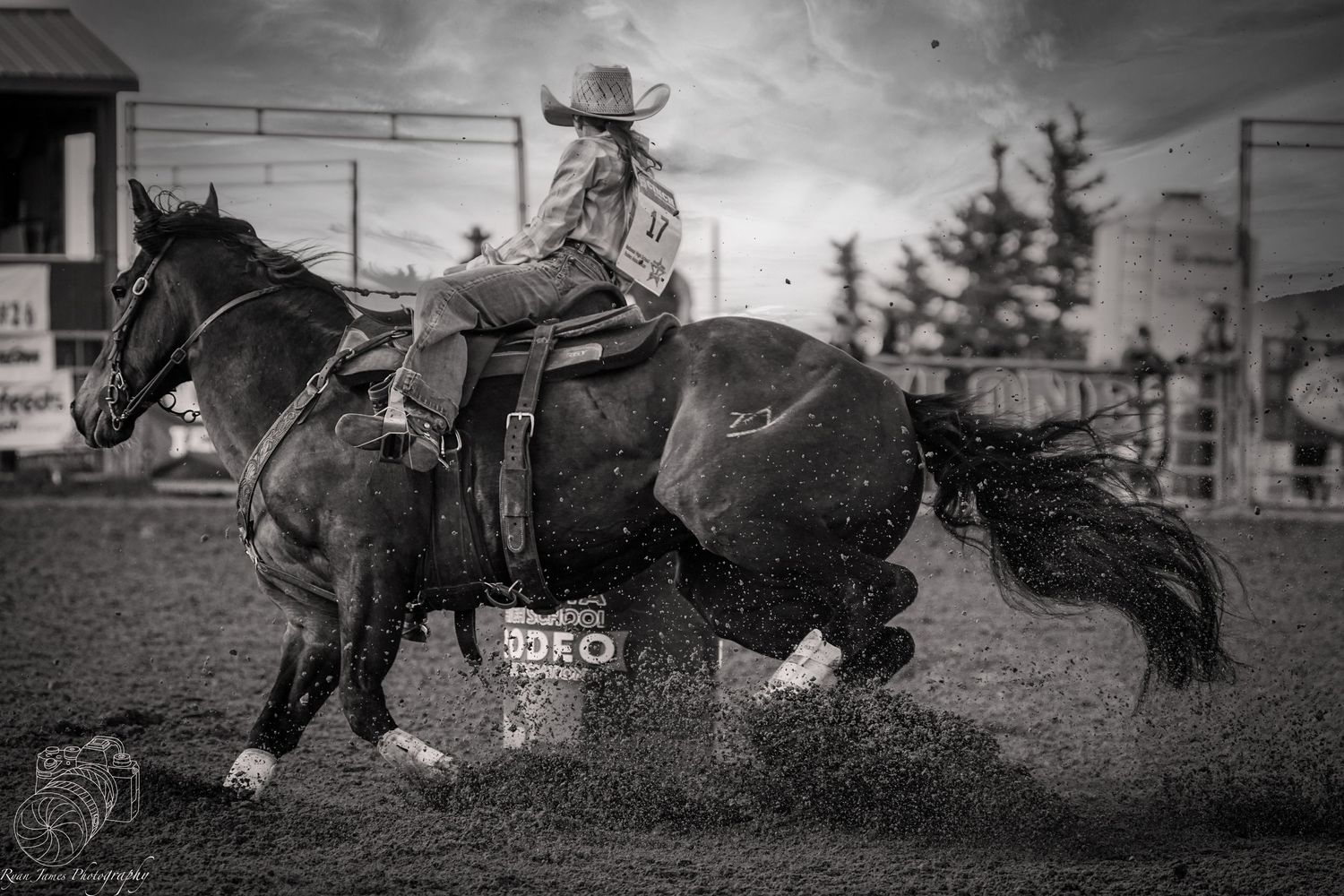 Black and white photo of a rodeo rider on a horse during a barrel racing competition.