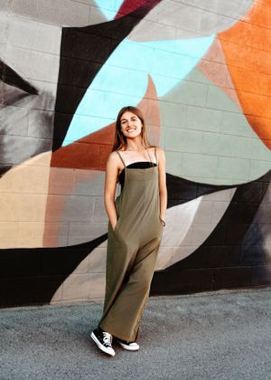 Stylish casual outfit against colorful geometric wall mural with orange, blue and black shapes.