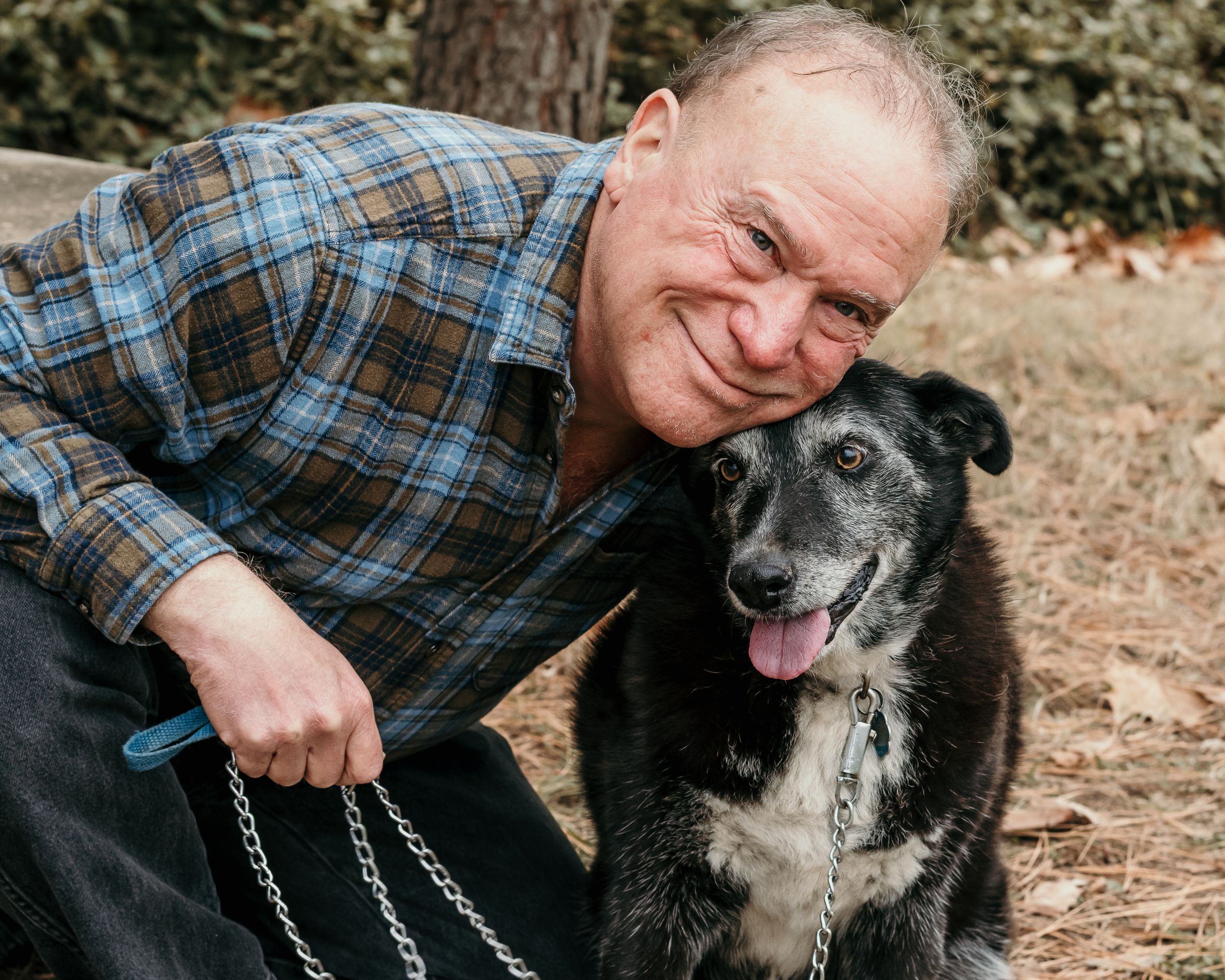 A man poses, smiling, with his dog.