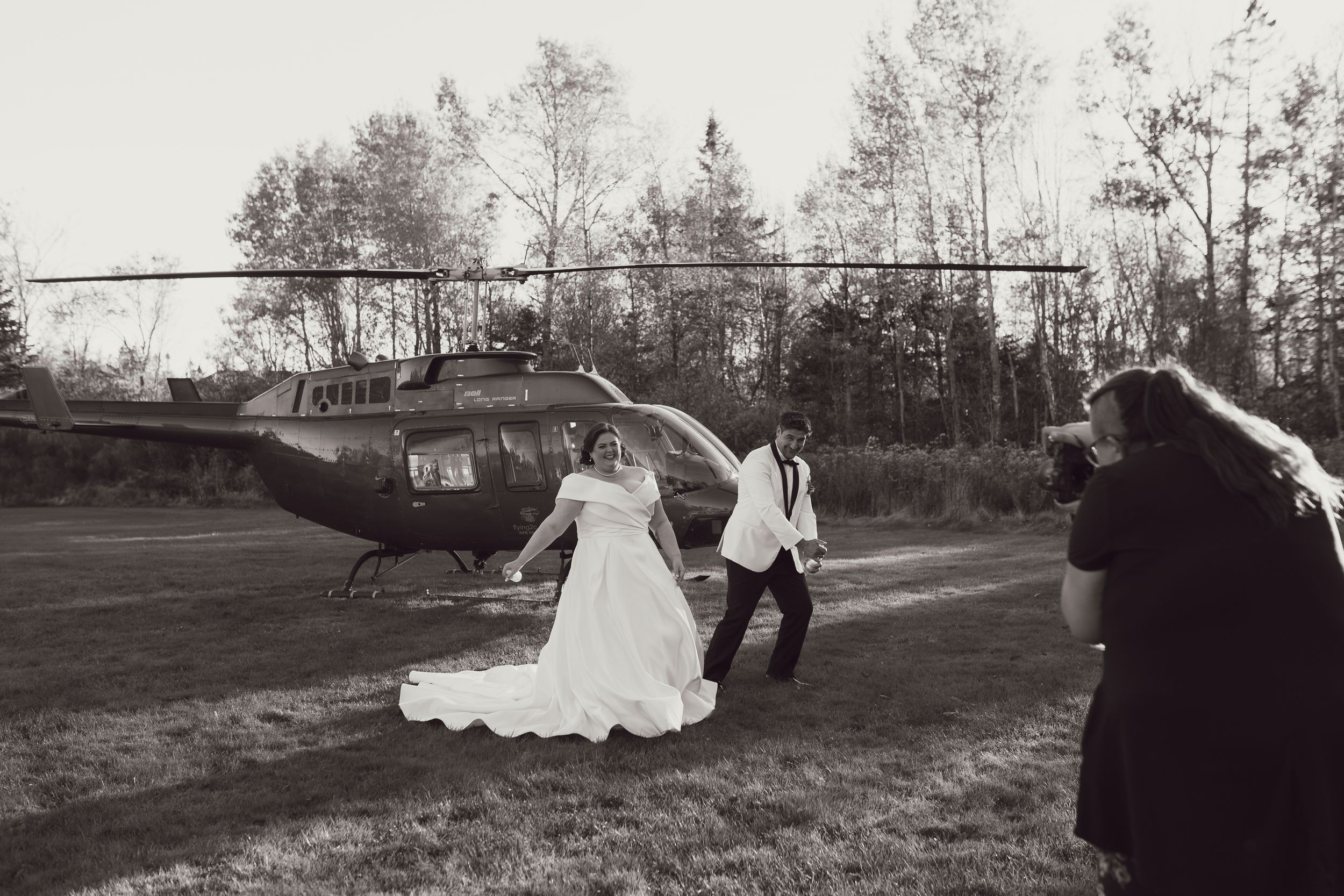 Black and white wedding photo with helicopter in background.