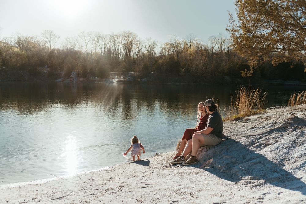 People relaxing on a white sandy beach beside a tranquil lake.