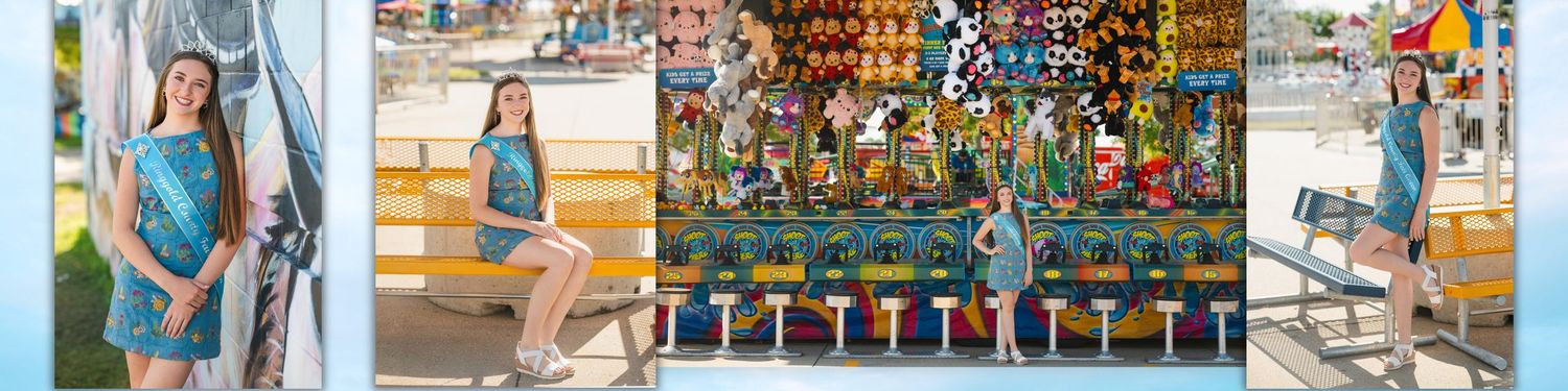 Young girl in teal dress poses at a colorful carnival game booth during a sunny outdoor fair.