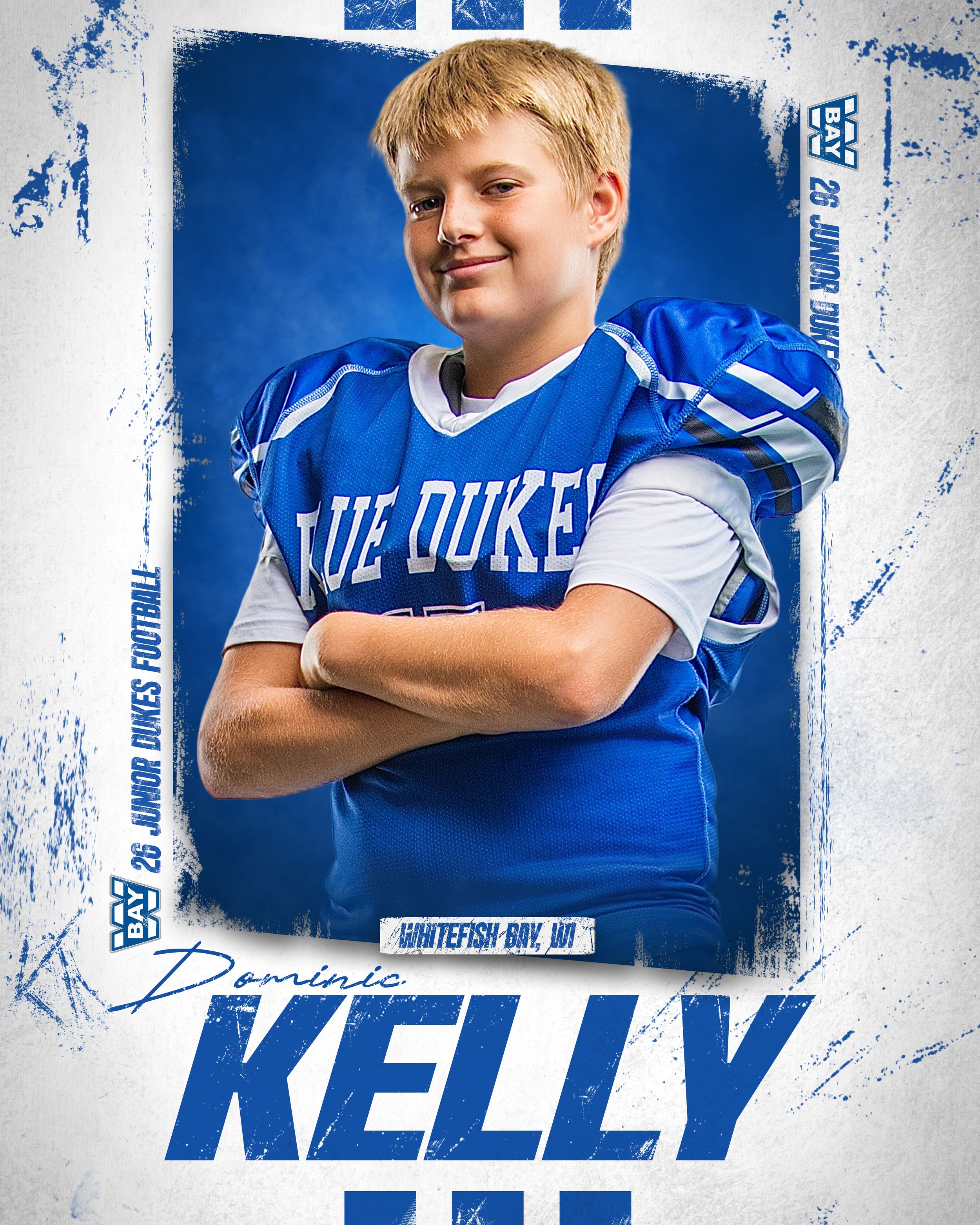 Young football player Dominic Kelly in Blue Dukes jersey poses with arms crossed for Whitefish Bay, WI junior football team photo.