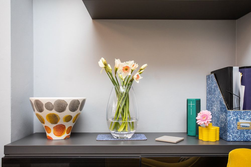 Office shelf display with polka dot bowl, glass vase of pink flowers and stationery.