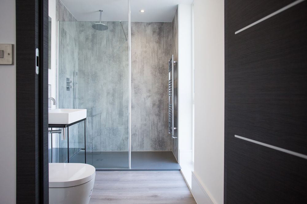 Modern minimalist bathroom with walk-in shower, grey stone tiles and glass partition.
