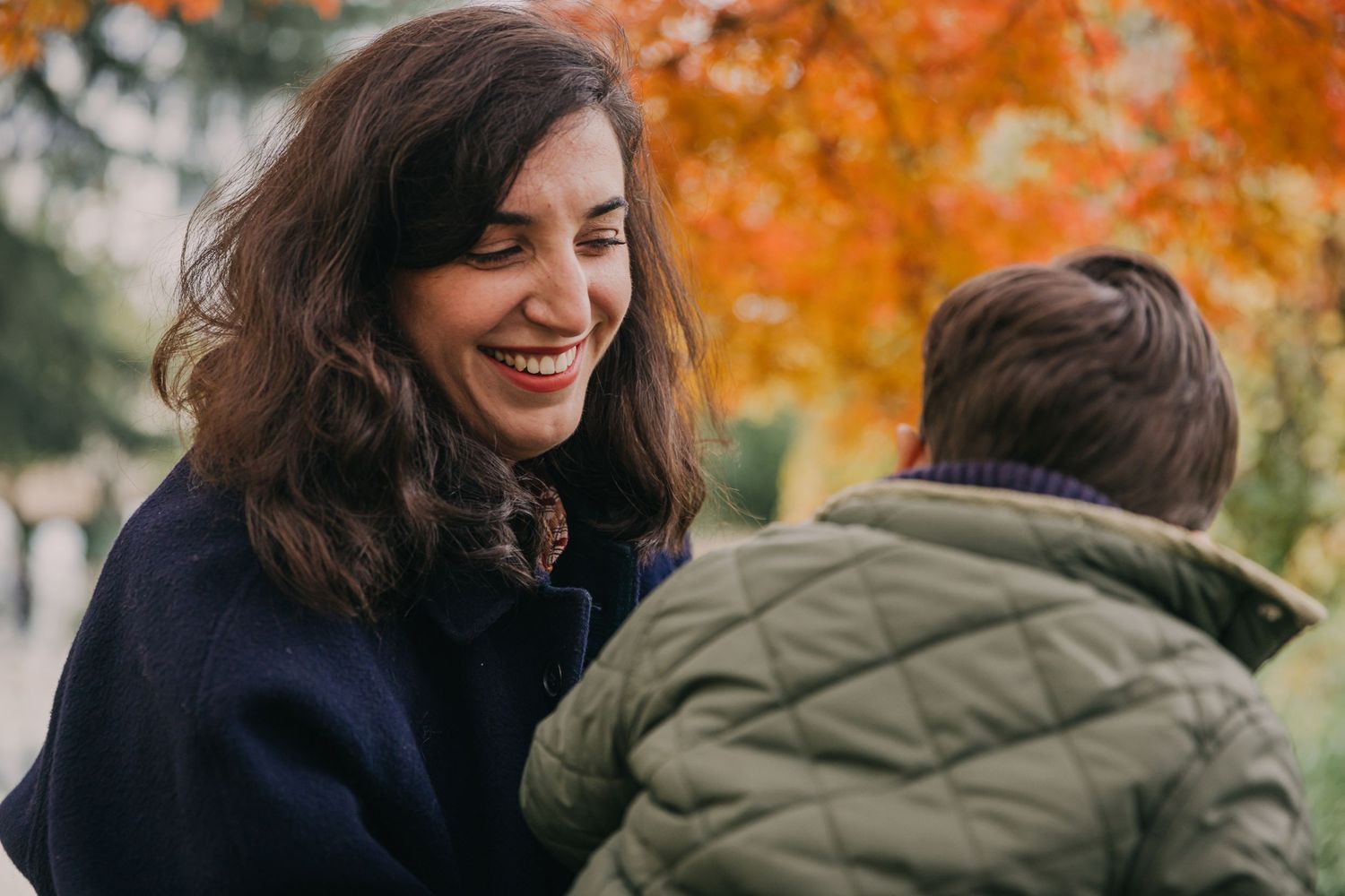 Une maman regarde tendrement son fils alors qu'ils discutent sous un érable paré de ses couleurs d'automne à Courbevoie