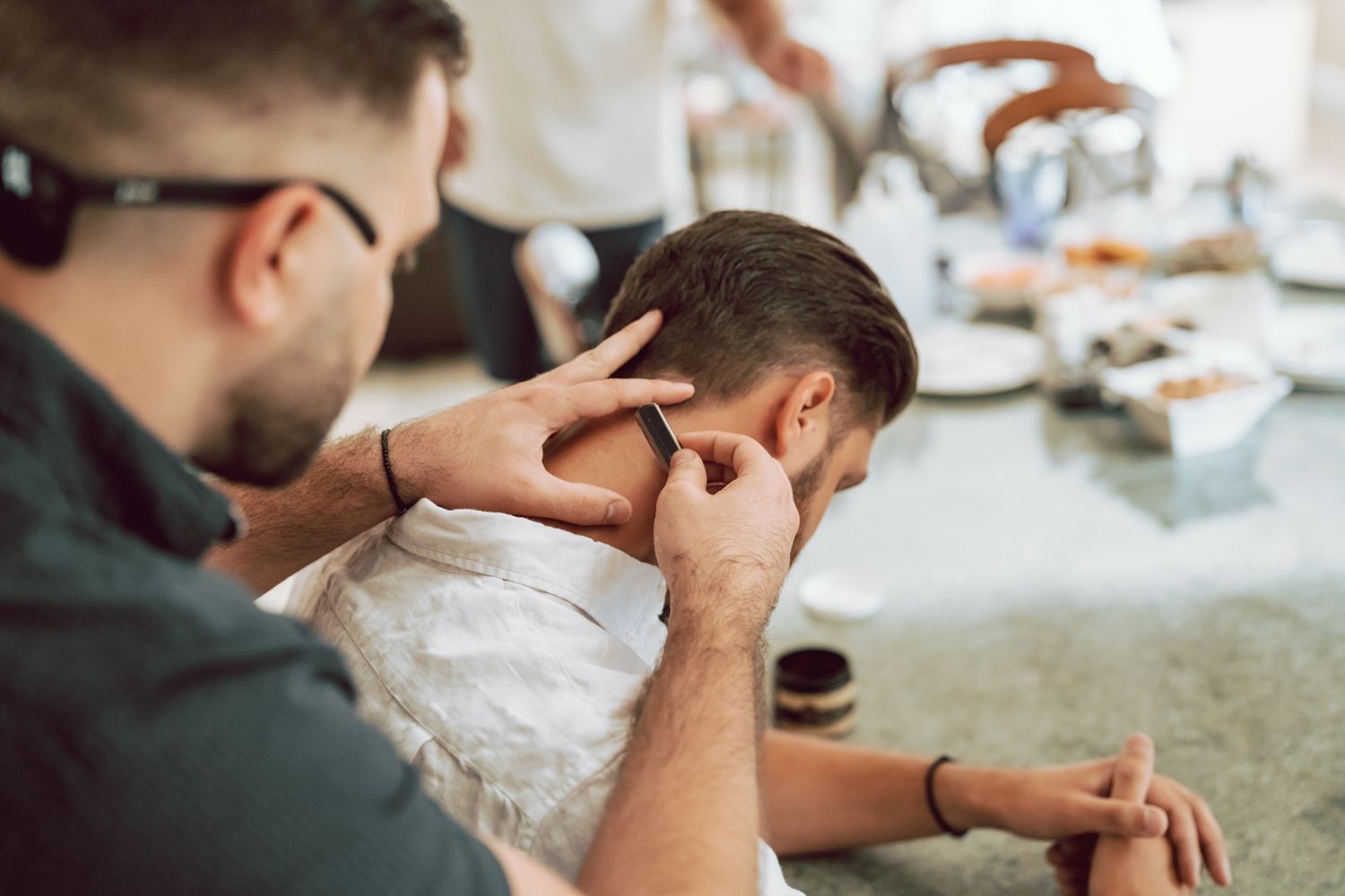 A barber carefully trims the neckline of a male client during a professional haircut session indoors.