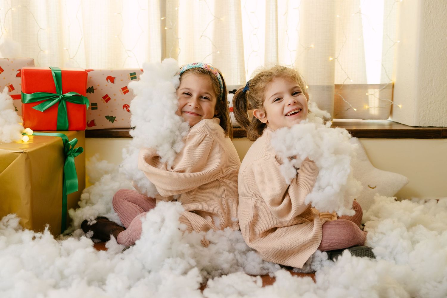 Child in red plaid pajamas poses playfully on white bedding.