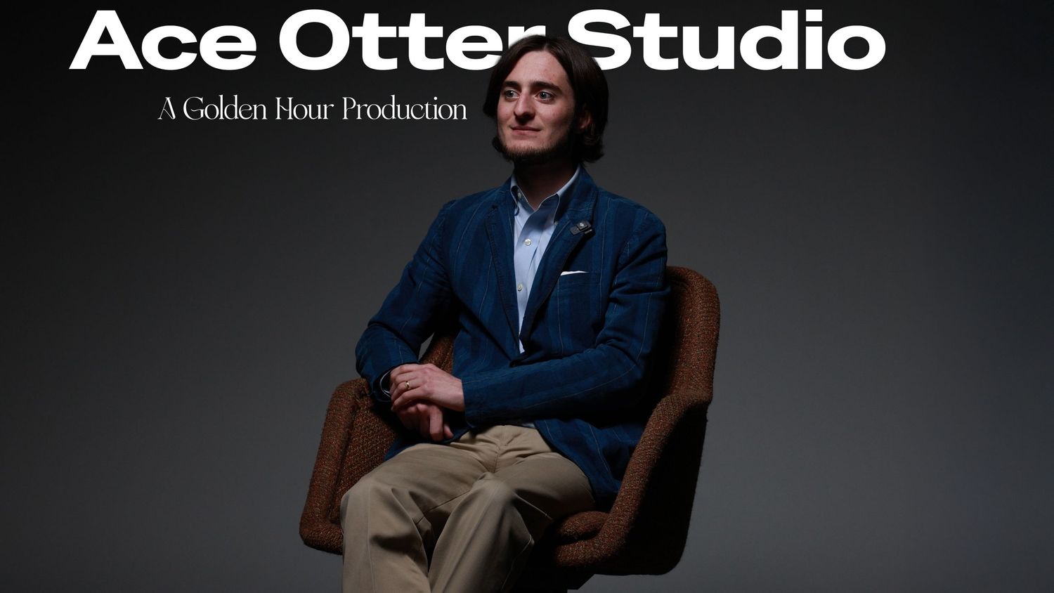 Man in blue blazer sits in leather chair under Ace Otter Studio golden hour production branding.