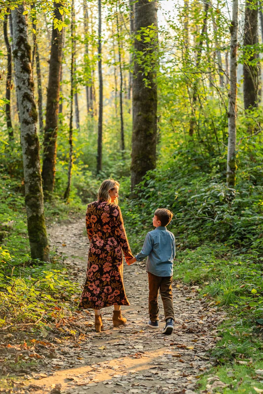 Mom and son walking in a forest and there's backlit by the sunlight.
