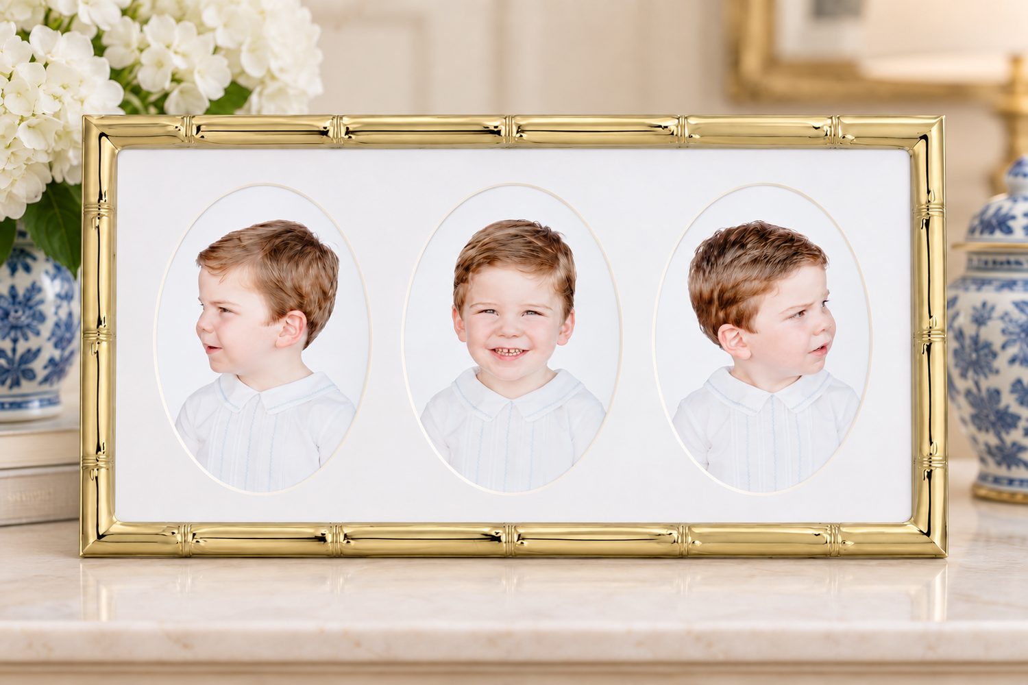 Gold bamboo triple photo frame displaying three oval portraits of a young boy in white shirt on a marble surface.