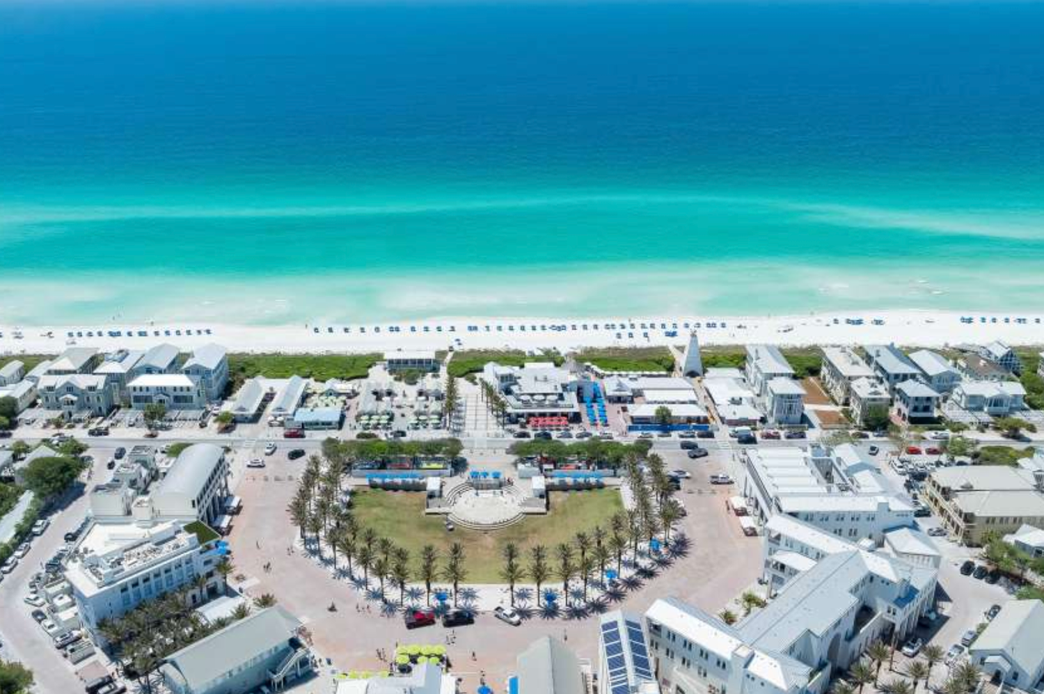 Aerial view of a coastal Florida beach town with turquoise Gulf waters, white sandy shores, and a charming town square.