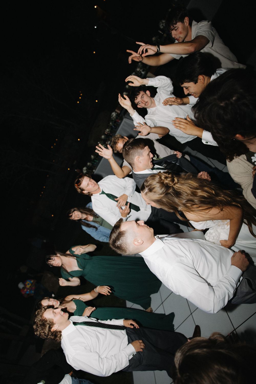 Wedding guests in formal attire dance energetically on dark reception dance floor.
Great Falls Montana, Milo Creek Wedding photographer