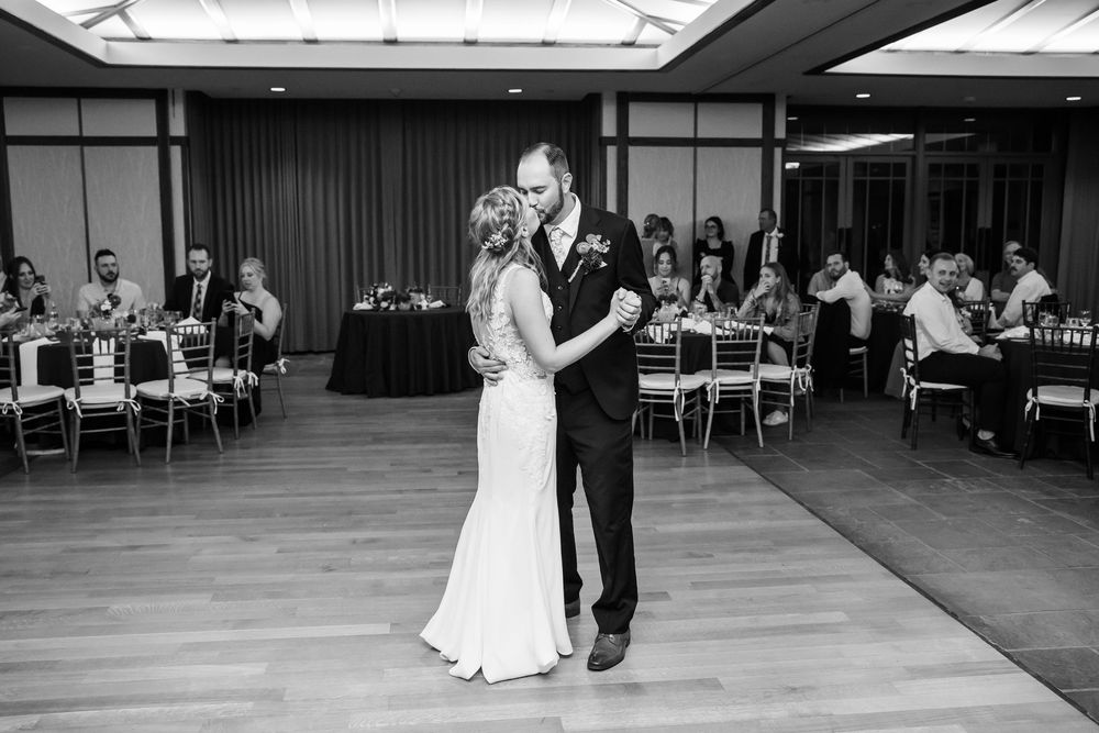 Black and white photo of bride and groom sharing their first dance at elegant wedding reception.