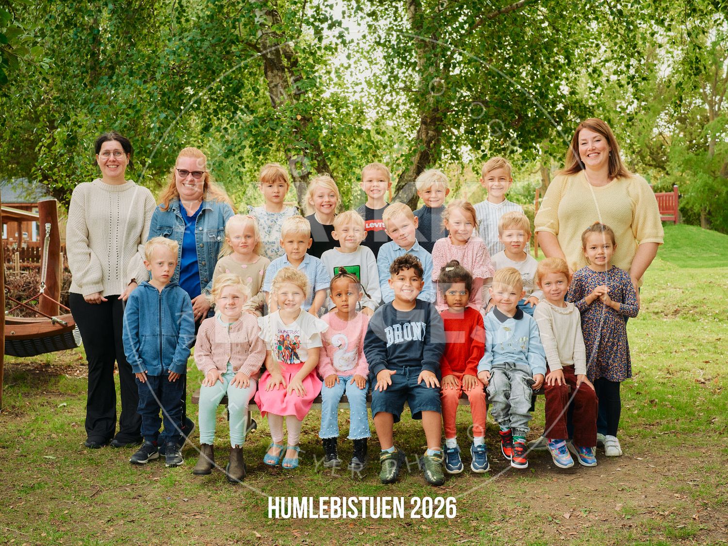 Group photo of children and teachers at Humlebistuen 2026 outdoor school portrait in a green garden setting.