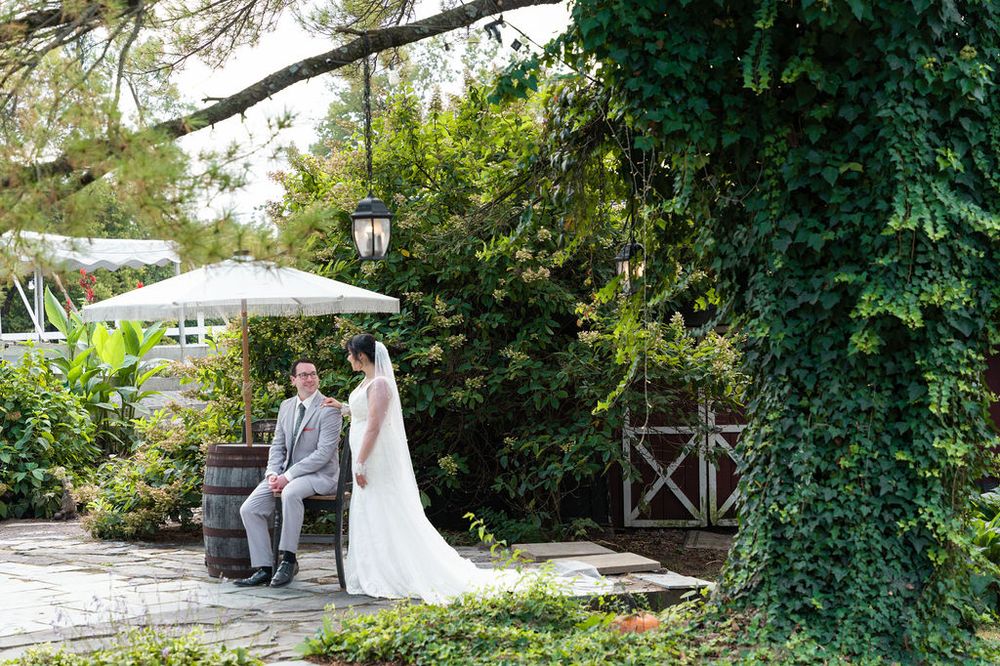 A bride and groom share a romantic moment in a lush garden setting with ivy-covered walls on their wedding day.