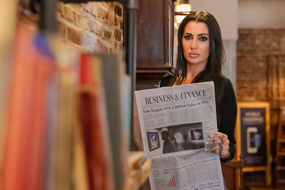 Person reading a newspaper in a cozy indoor setting with brick walls and warm lighting.