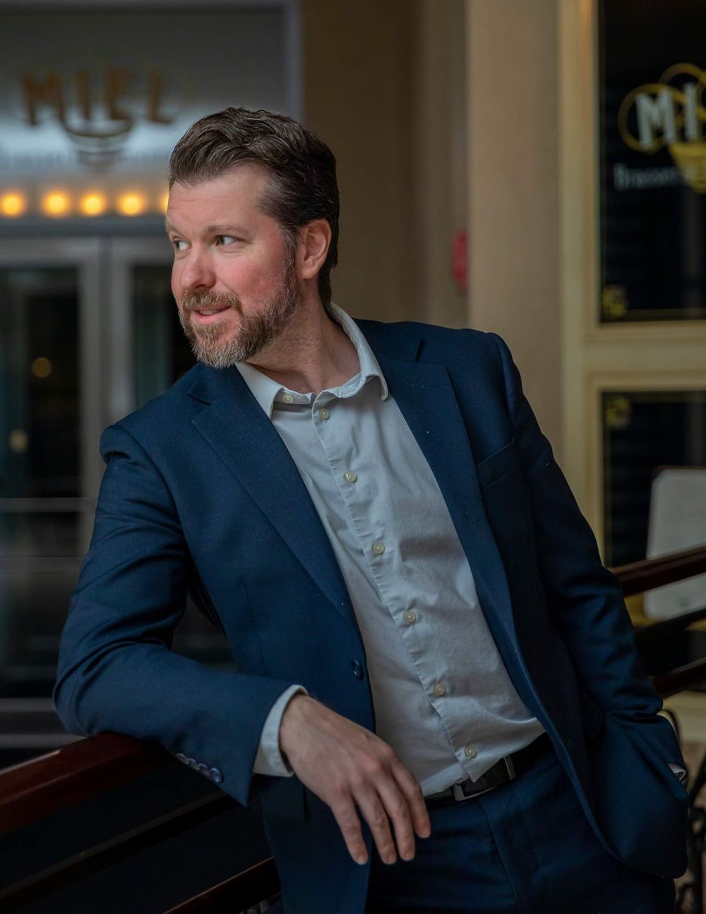 Professional business portrait series in navy suit against dark background.