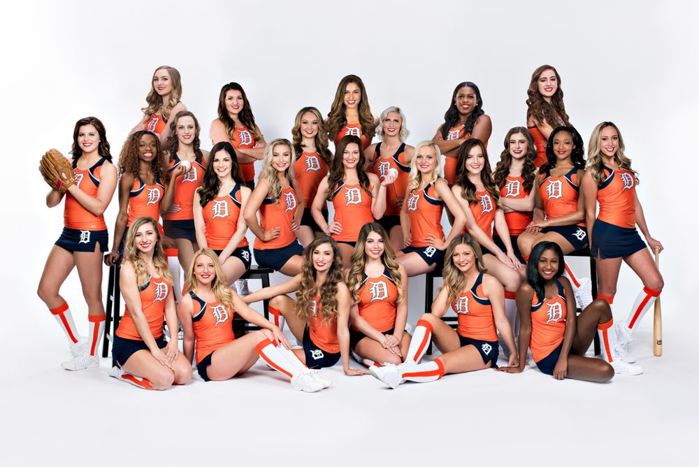 Detroit Tigers dance team poses in orange and navy uniforms with baseball bats for official team photo.