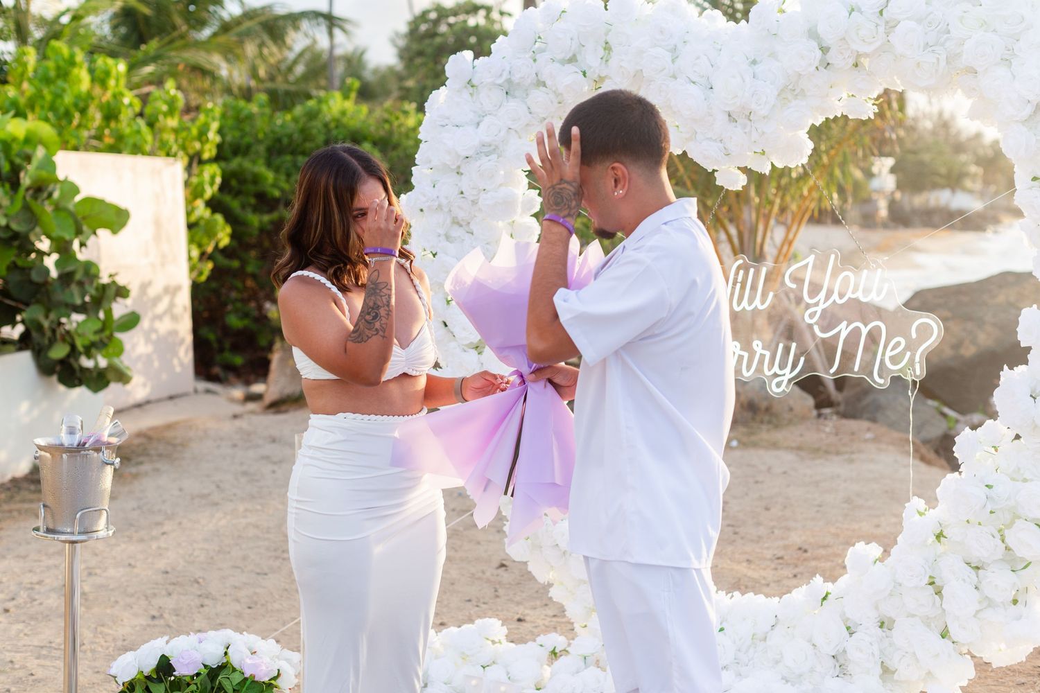 Marriage proposal. Man, woman, and decorative setup with white flower heart overlooking the ocean in Río Grande, Puerto Rico.