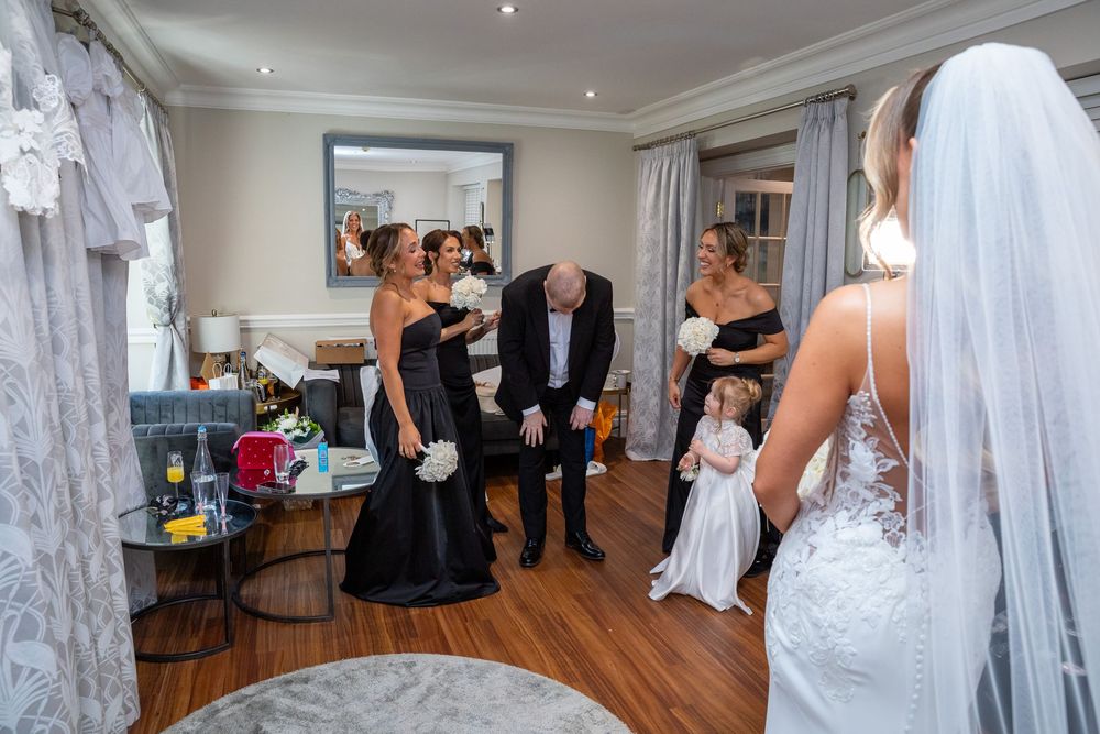 Emotional father reacts to seeing his daughter in her wedding dress surrounded by bridesmaids.