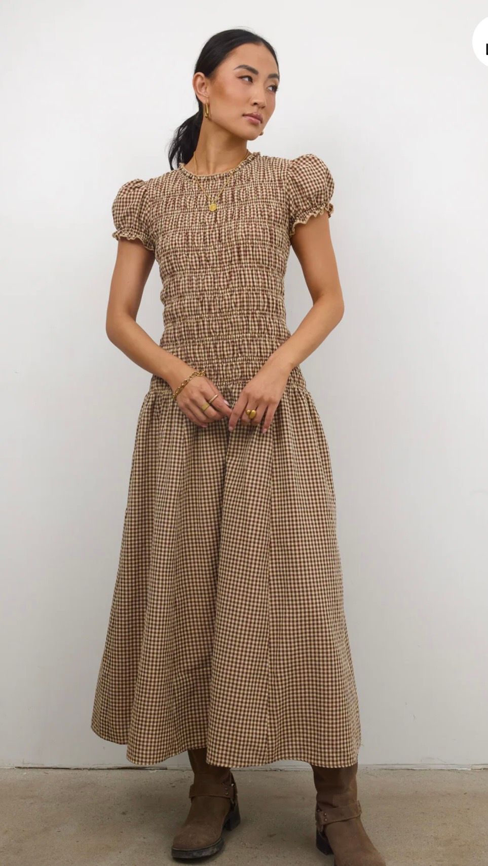 Woman wearing a brown gingham smocked bodice midi dress with puff sleeves and brown ankle boots.