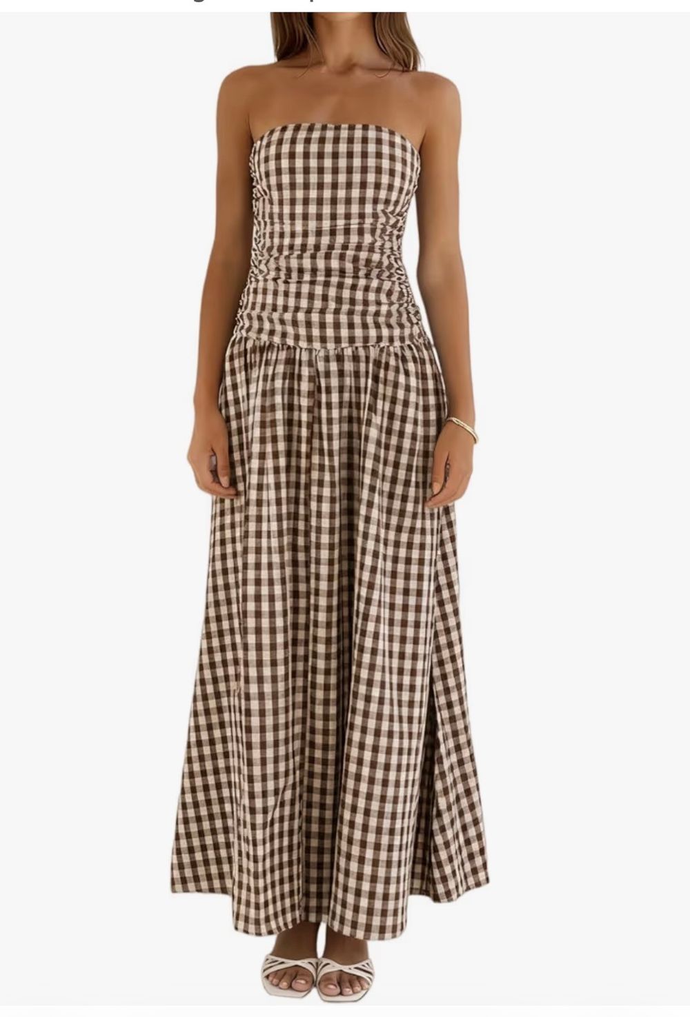 Woman wearing a strapless brown gingham check maxi dress with ruched bodice, pleated skirt, and side slit.