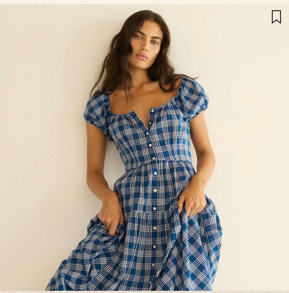 Woman wearing a blue plaid button-front midi dress with puff sleeves and sweetheart neckline.
