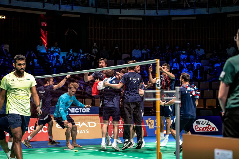Badminton players shake hands over the net after a competitive match at a Victor-sponsored indoor tournament.