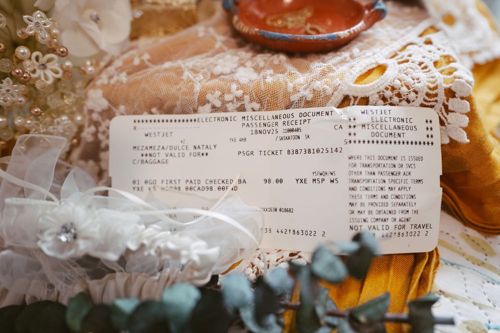 Vintage wedding flat lay with electronic receipt, lace garter, eucalyptus, and antique decorative items on lace fabric.