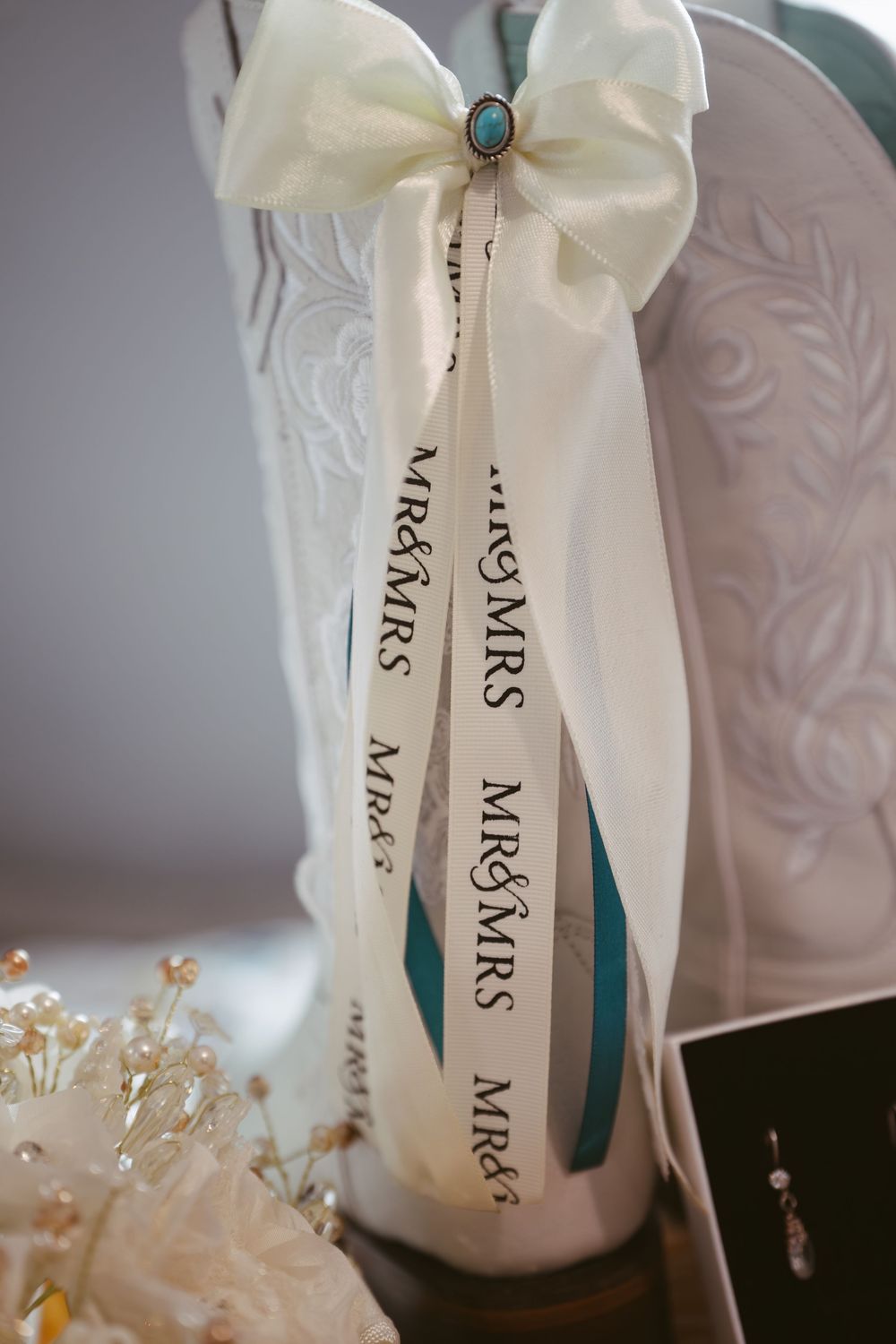 White cowboy boots with Mr & Mrs ribbon bow and turquoise stone accent for wedding.
