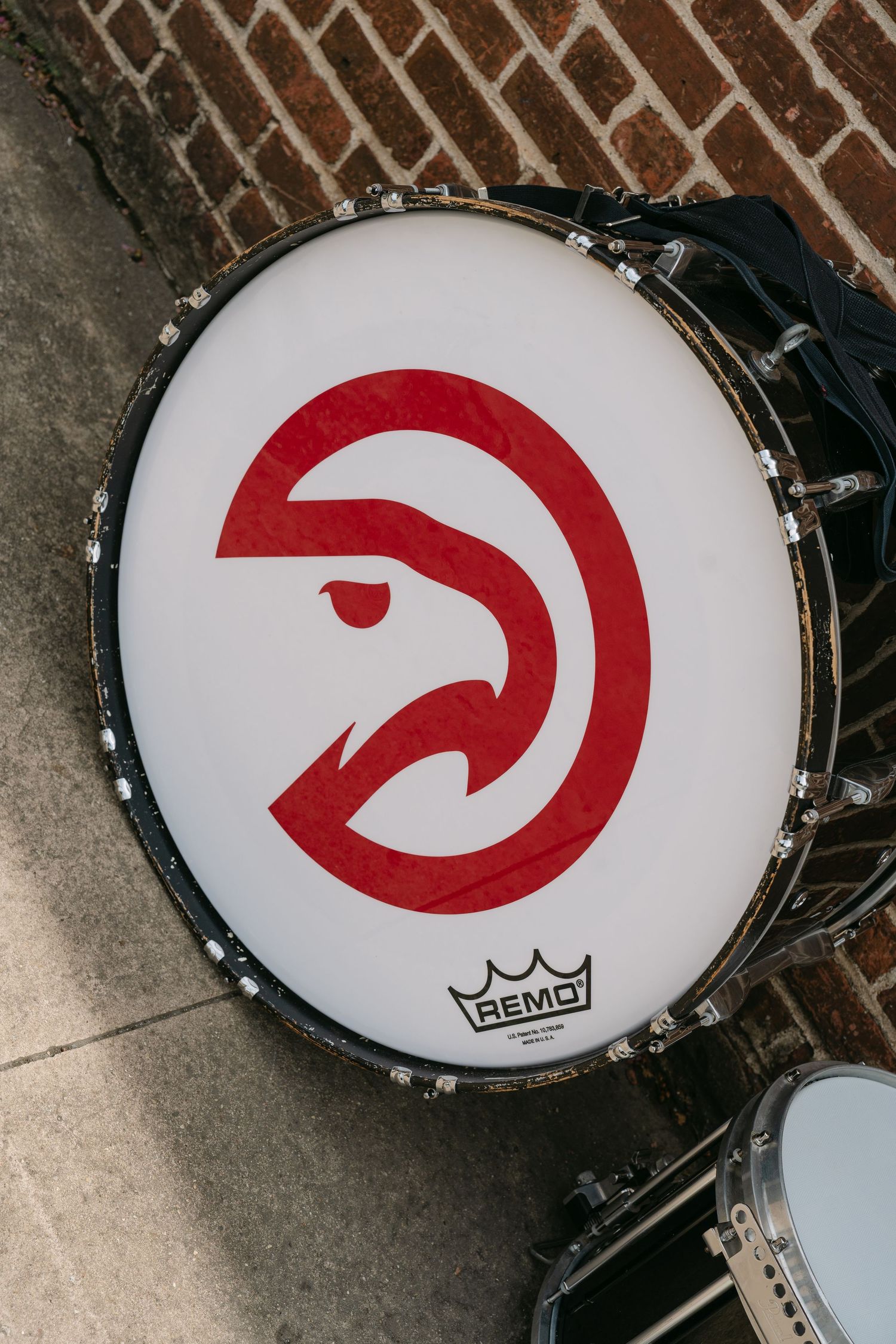 Atlanta Hawks NBA logo on a Remo bass drum head, displayed against a brick wall backdrop.